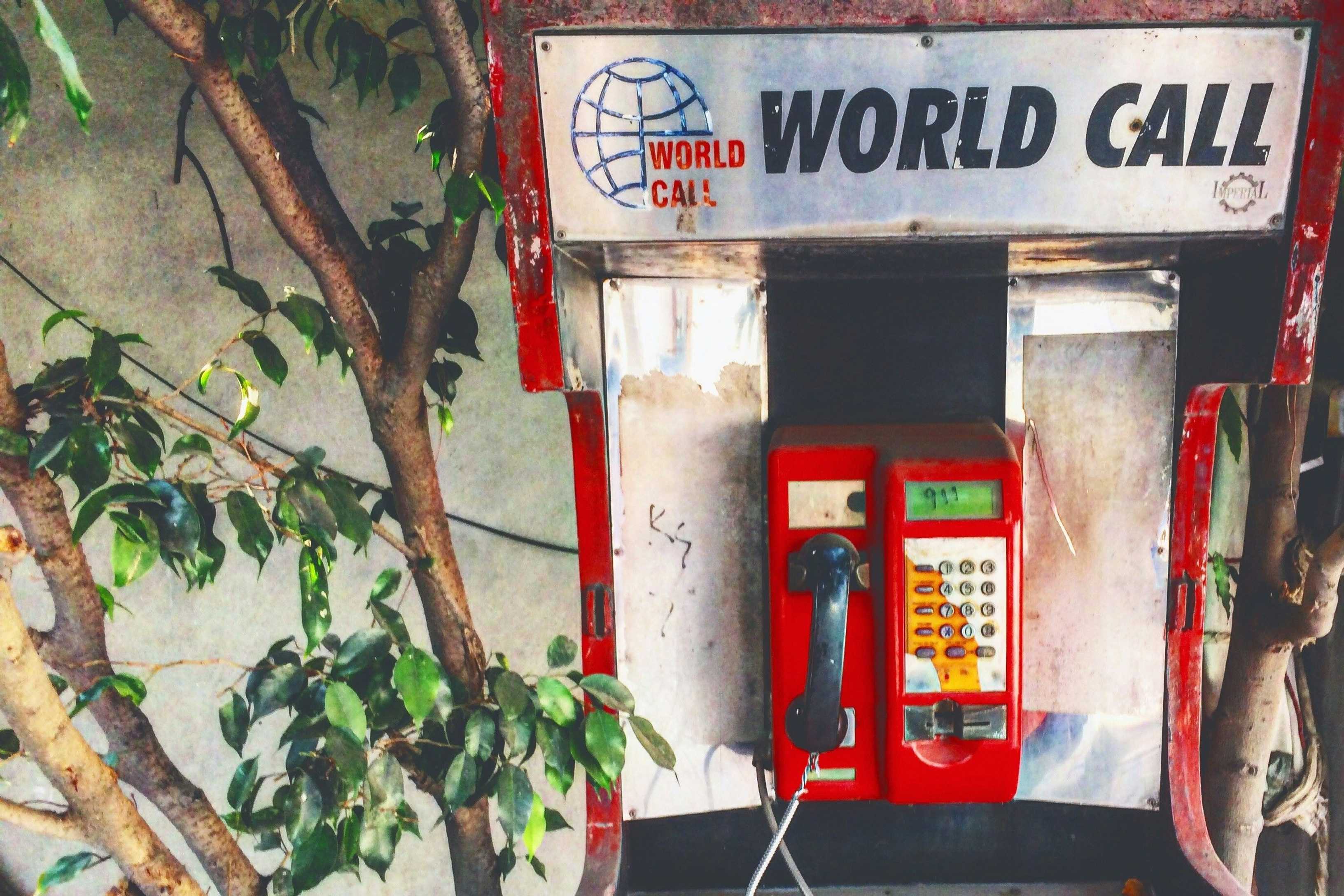 An old phone cell is mounted at a wall. It says World Call. On the screen someone painted 911.