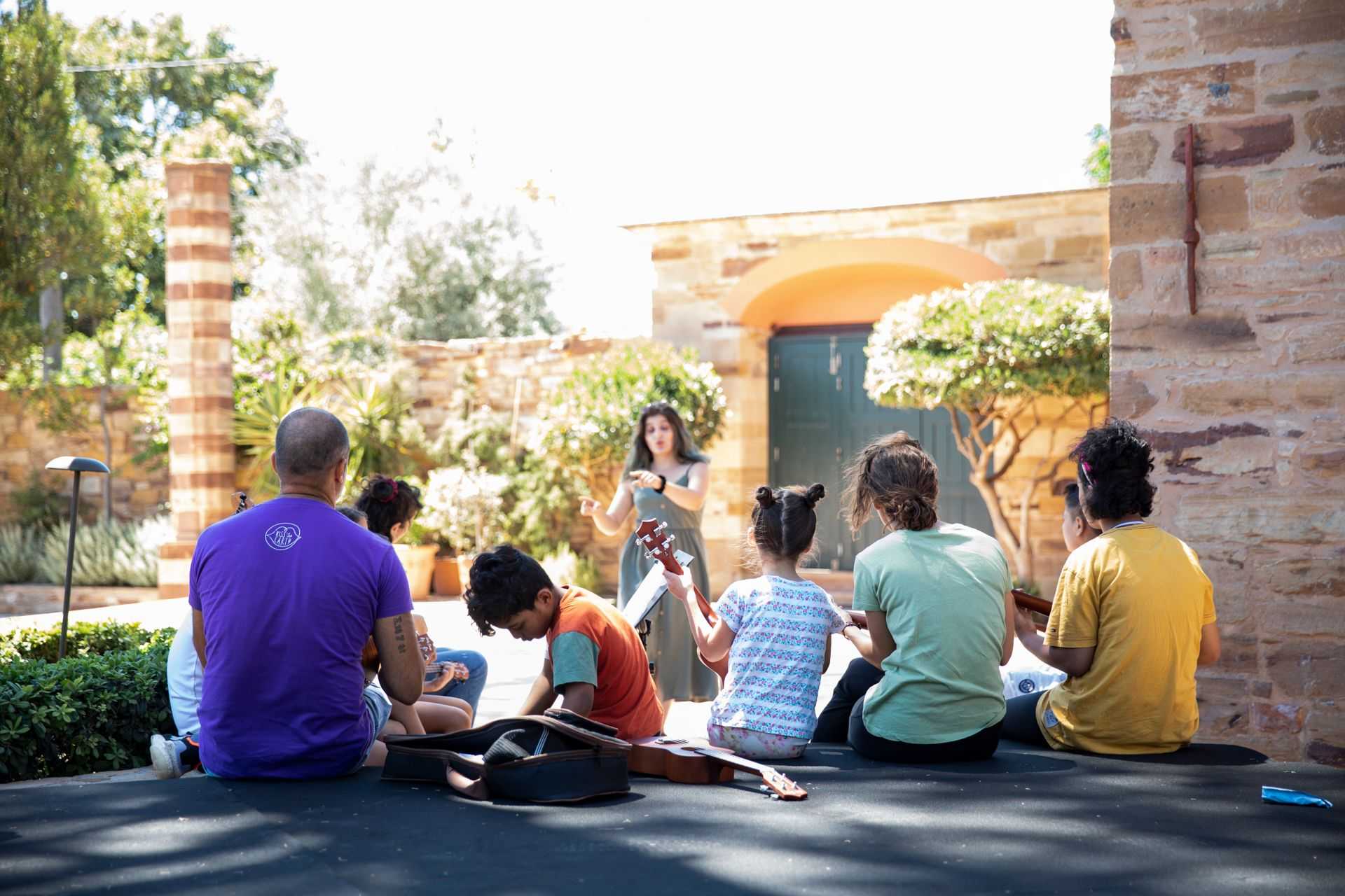 Two grown ups are sitting on a stonern scene with kids