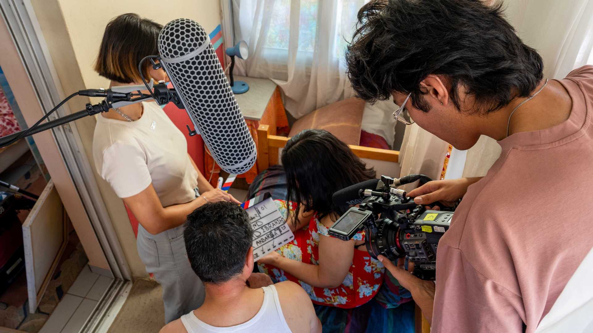 A group of students is working in a tiny studio on the editing of a movie.