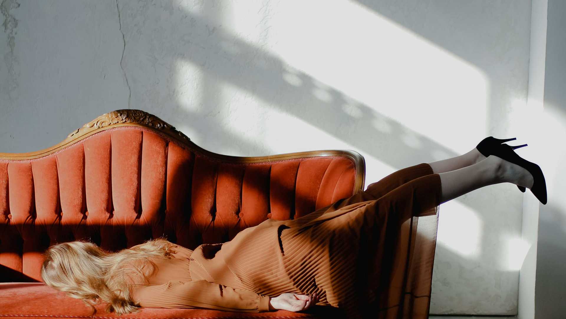 A woman is lying on a couch with her face turned towards the cotton