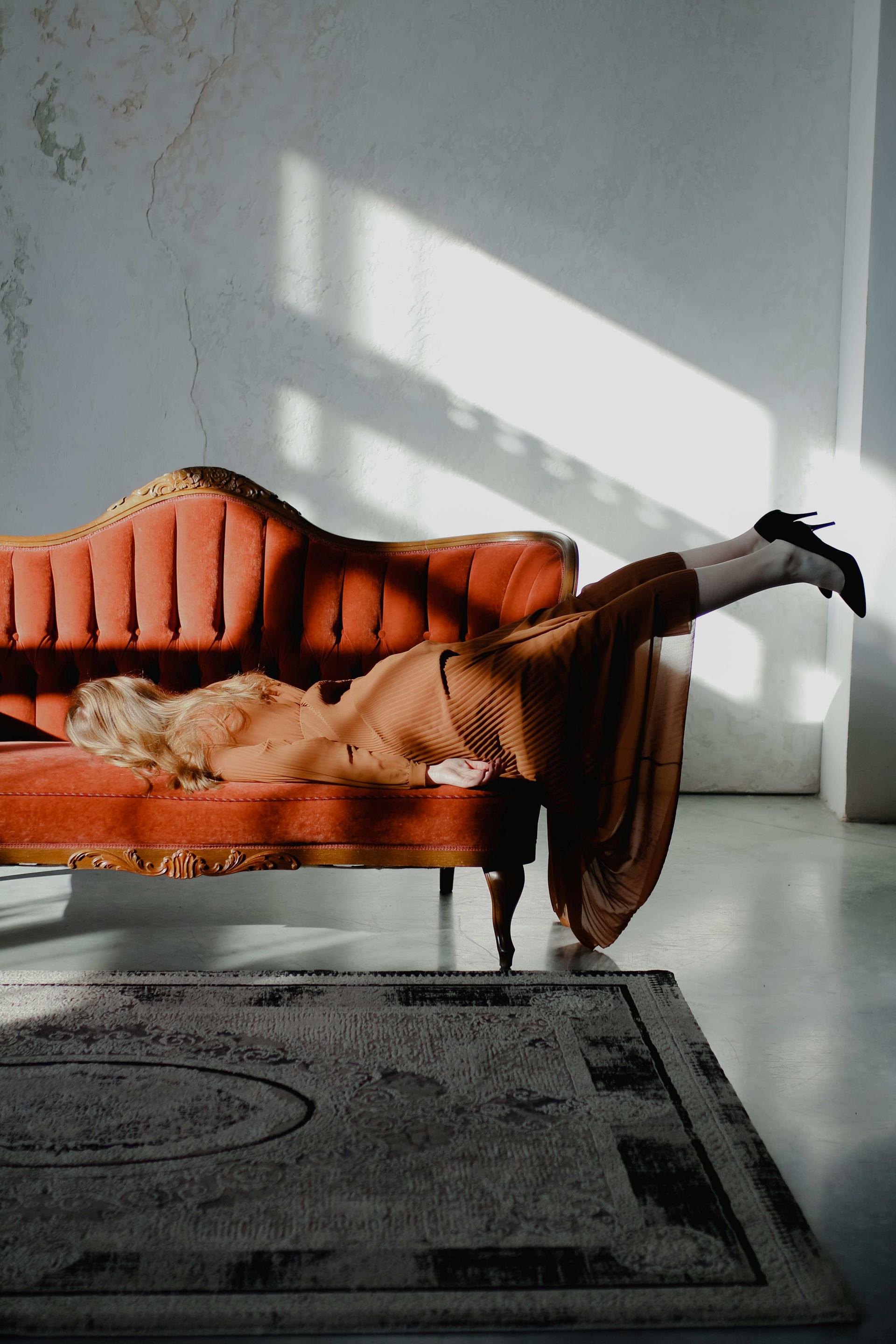 A woman is lying on a couch with her face turned towards the cotton