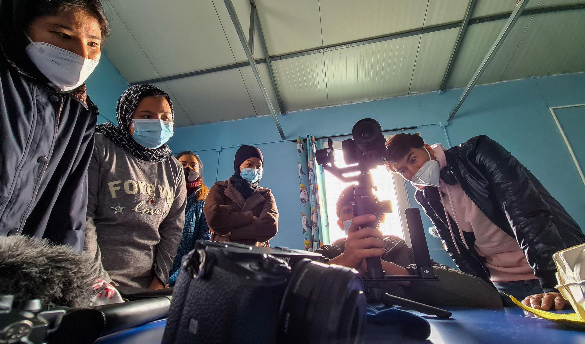 Yaser Akbari instructs students how to use a Gimbal. They are standing around him at a table, while he is explaining.