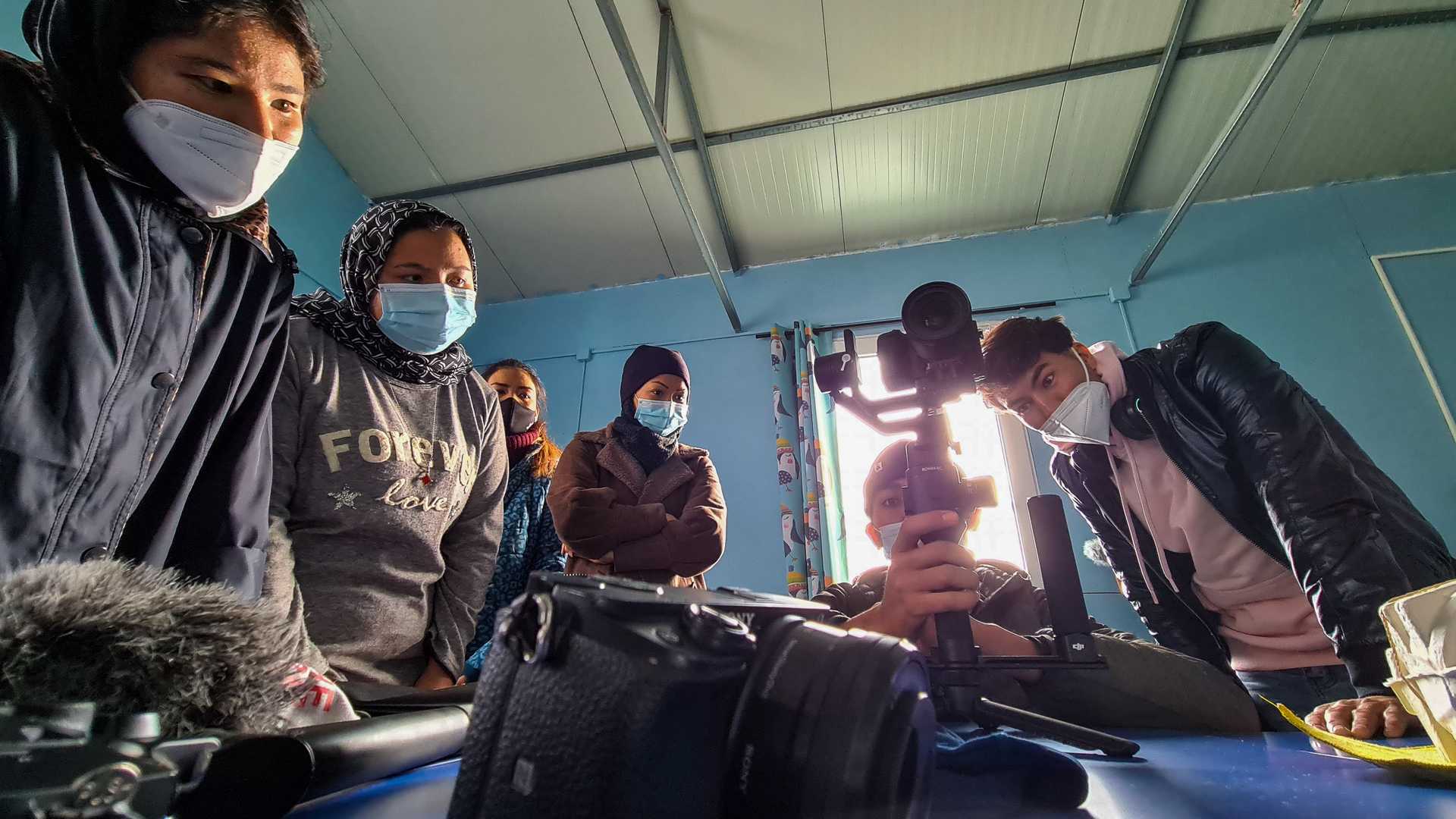Yaser Akbari instructs students how to use a Gimbal. They are standing around him at a table, while he is explaining.