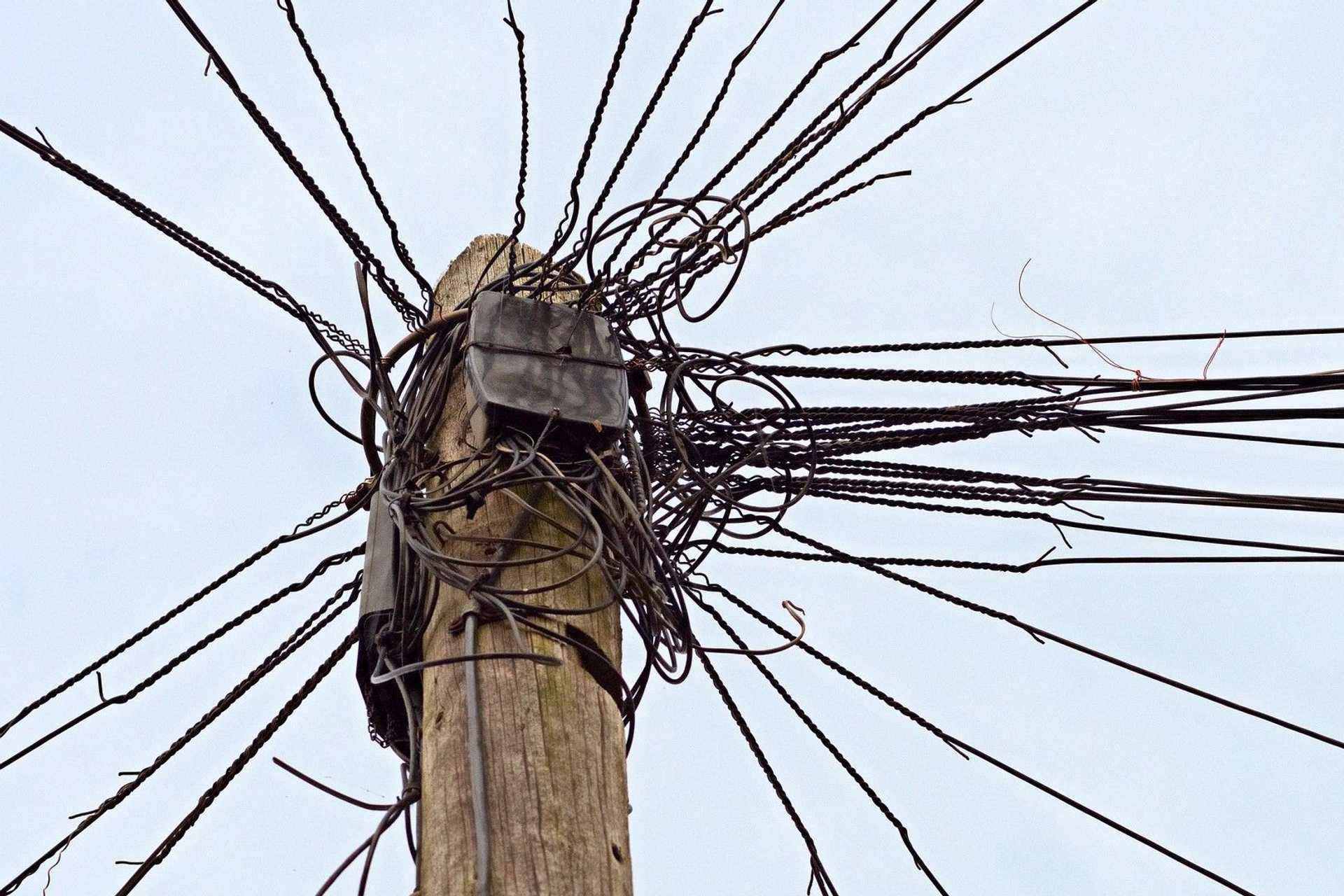 A wooden power pole with many electric wires