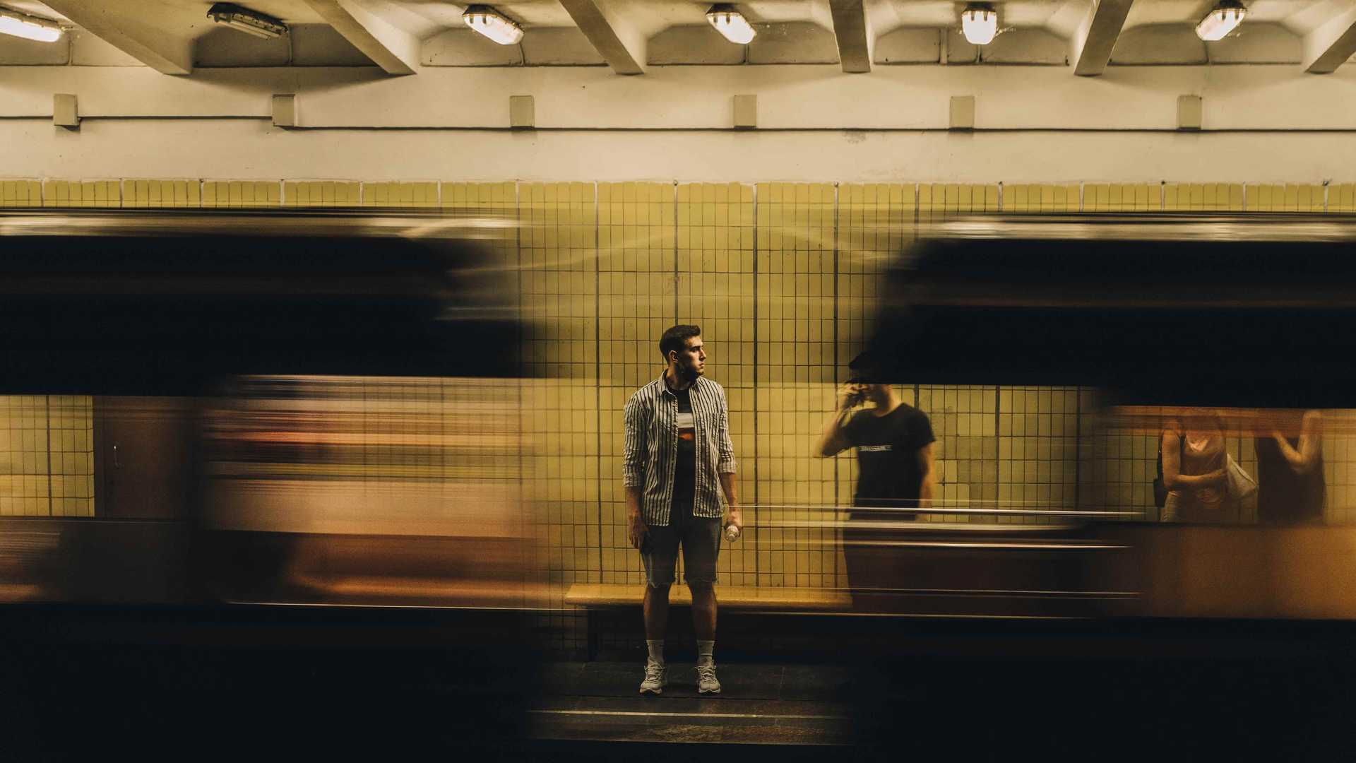A person is standing on a underground platform and a train is passing by.