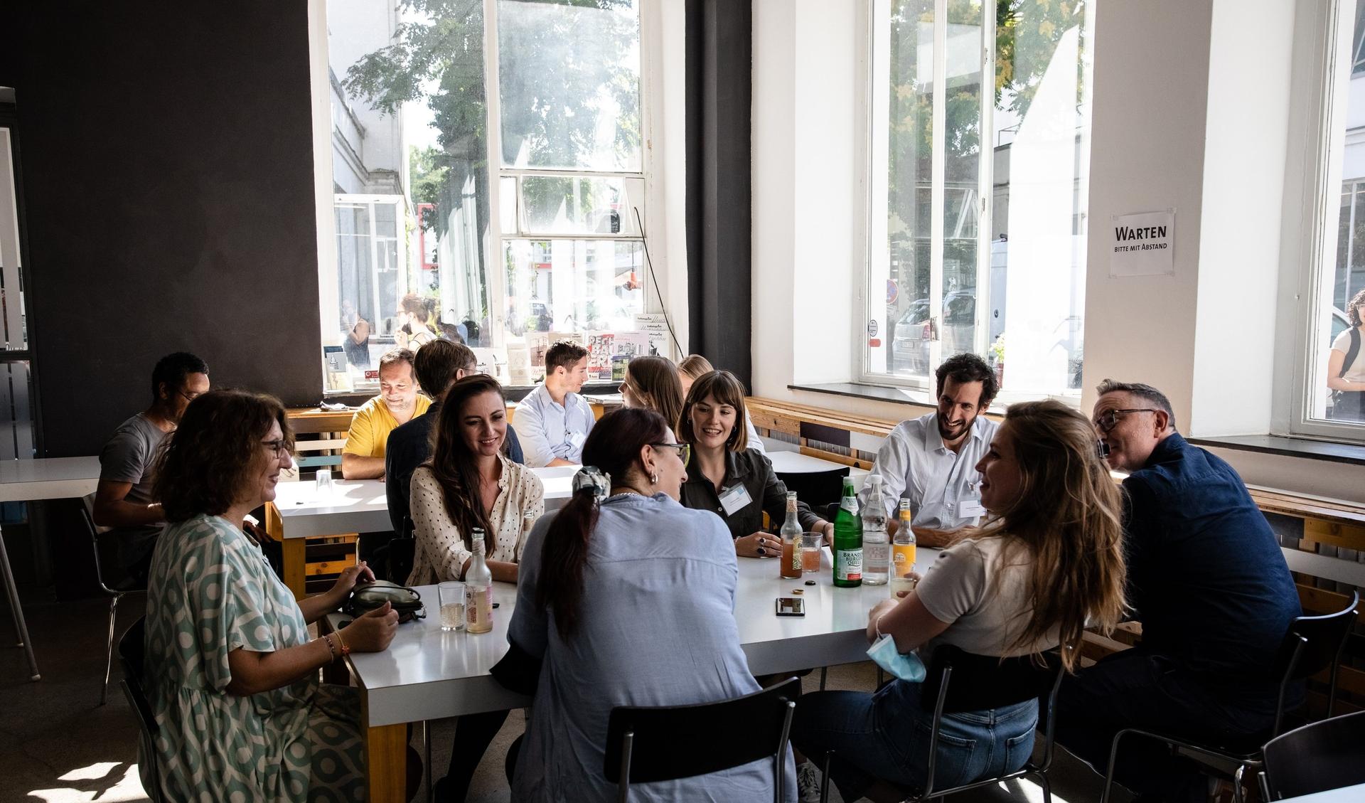 People sitting around a table and are talking to each other and laughing.