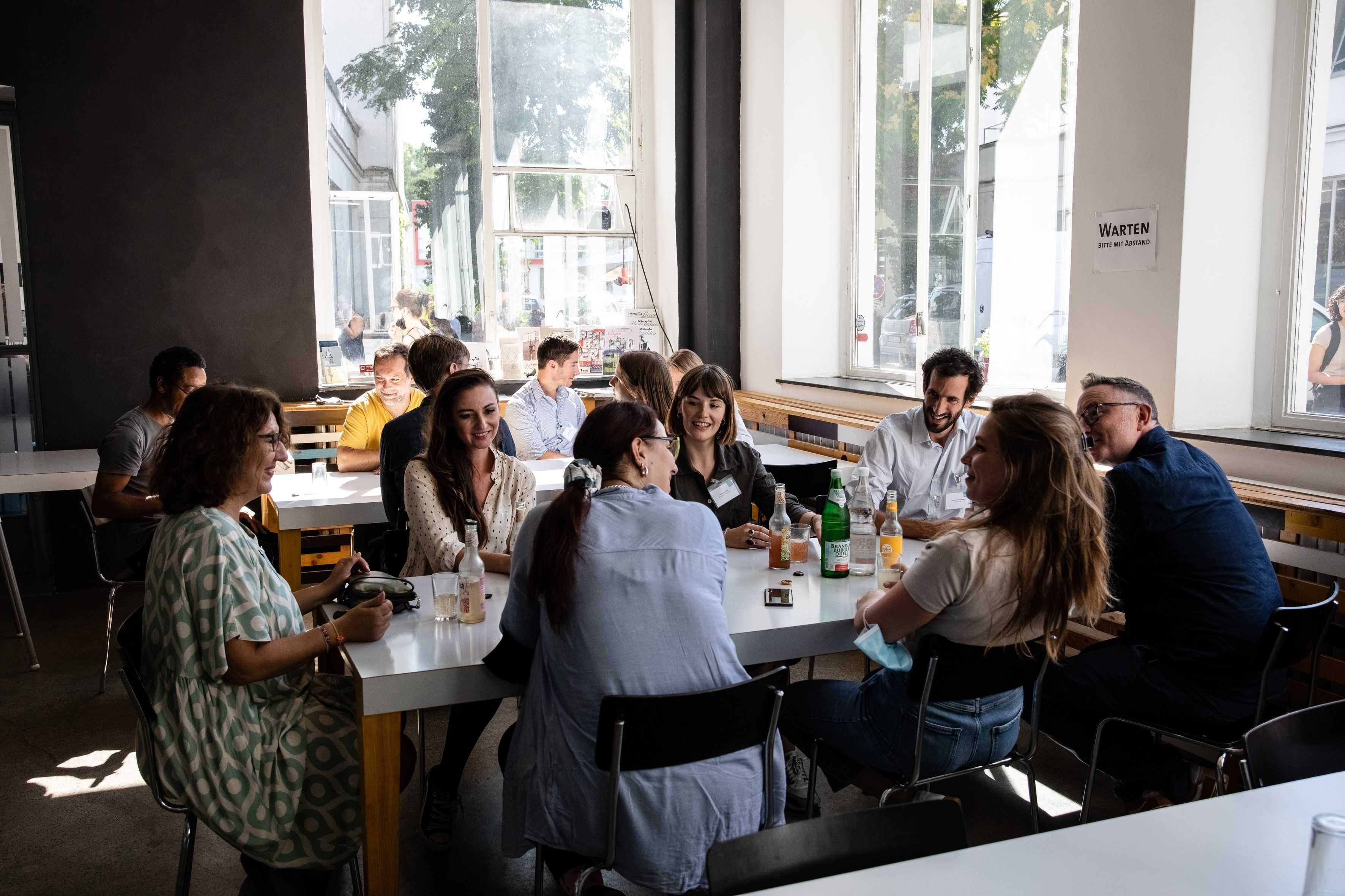 People sitting around a table and are talking to each other and laughing.