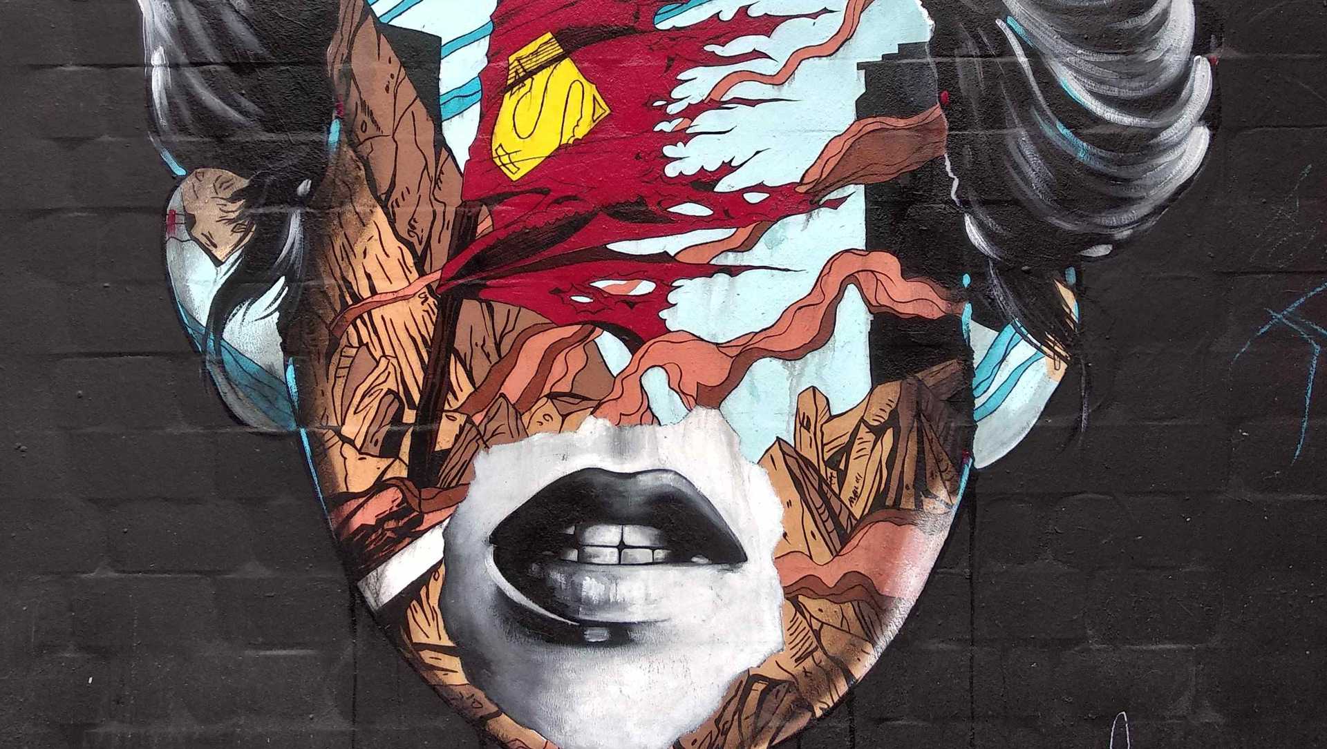 A mural with a face of a woman that has comic strips put over her face