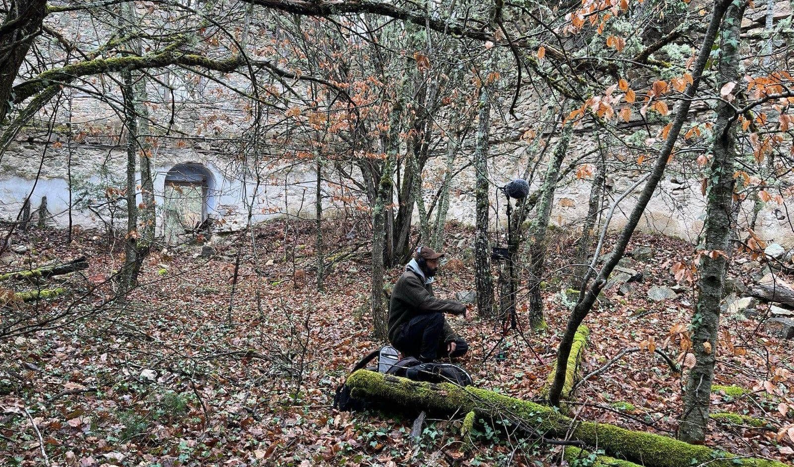 Stefanos Levidis kneels in the woods and is recording sounds