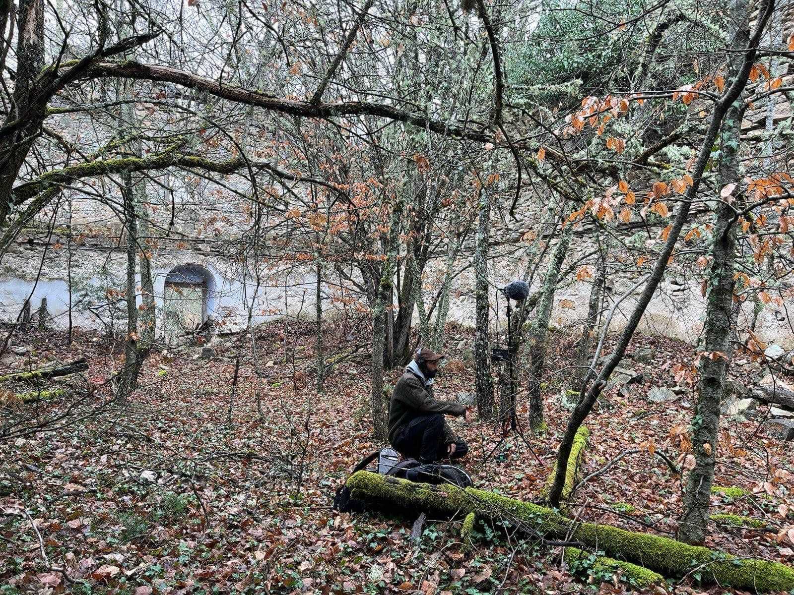 Stefanos Levidis kneels in the woods and is recording sounds