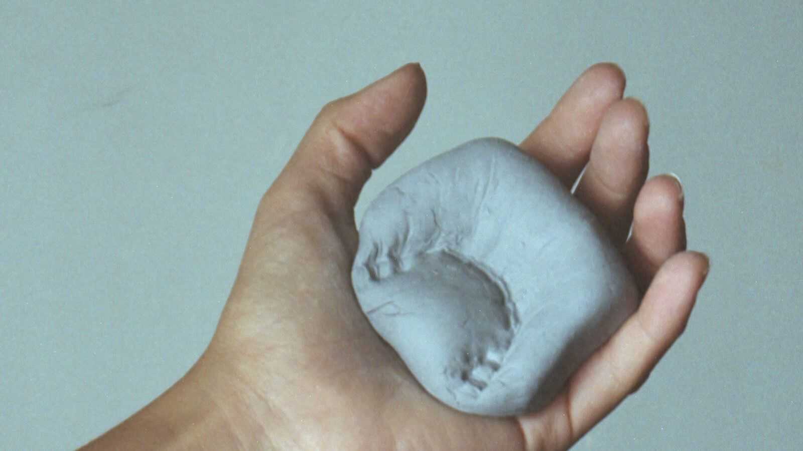 A hand holding a substance with a dental impression on it