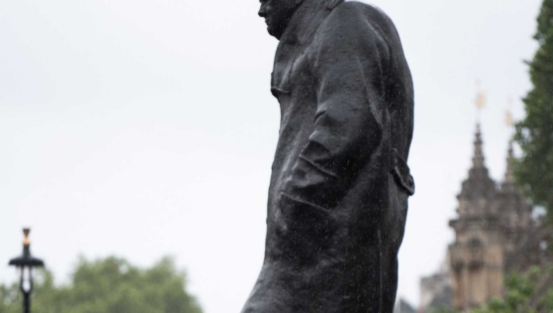A statute of Winston Churrchill in London. Beneath the statute a protest is taking place.