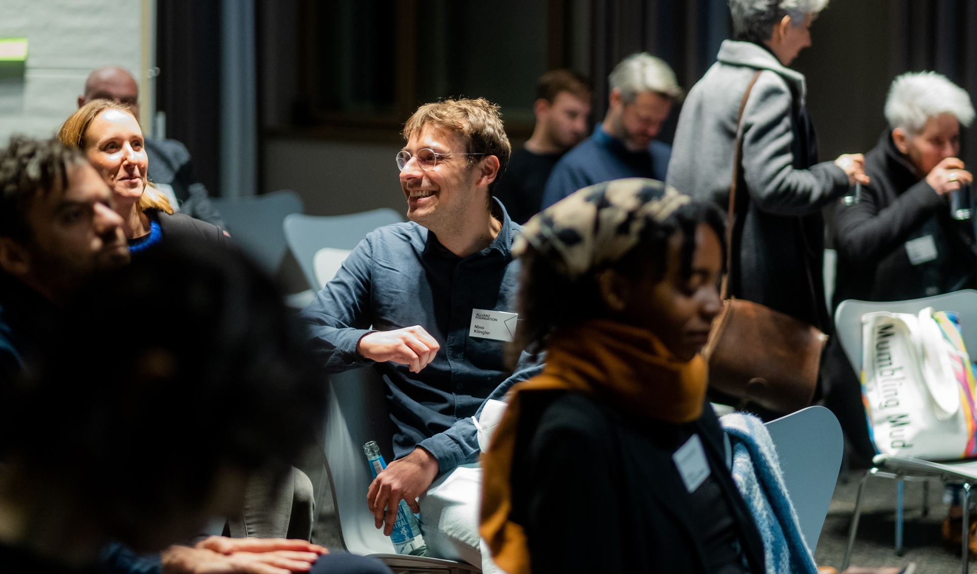 Allianz Foundation Team member sits in the middle of a room and turns around listening to someone speaking.