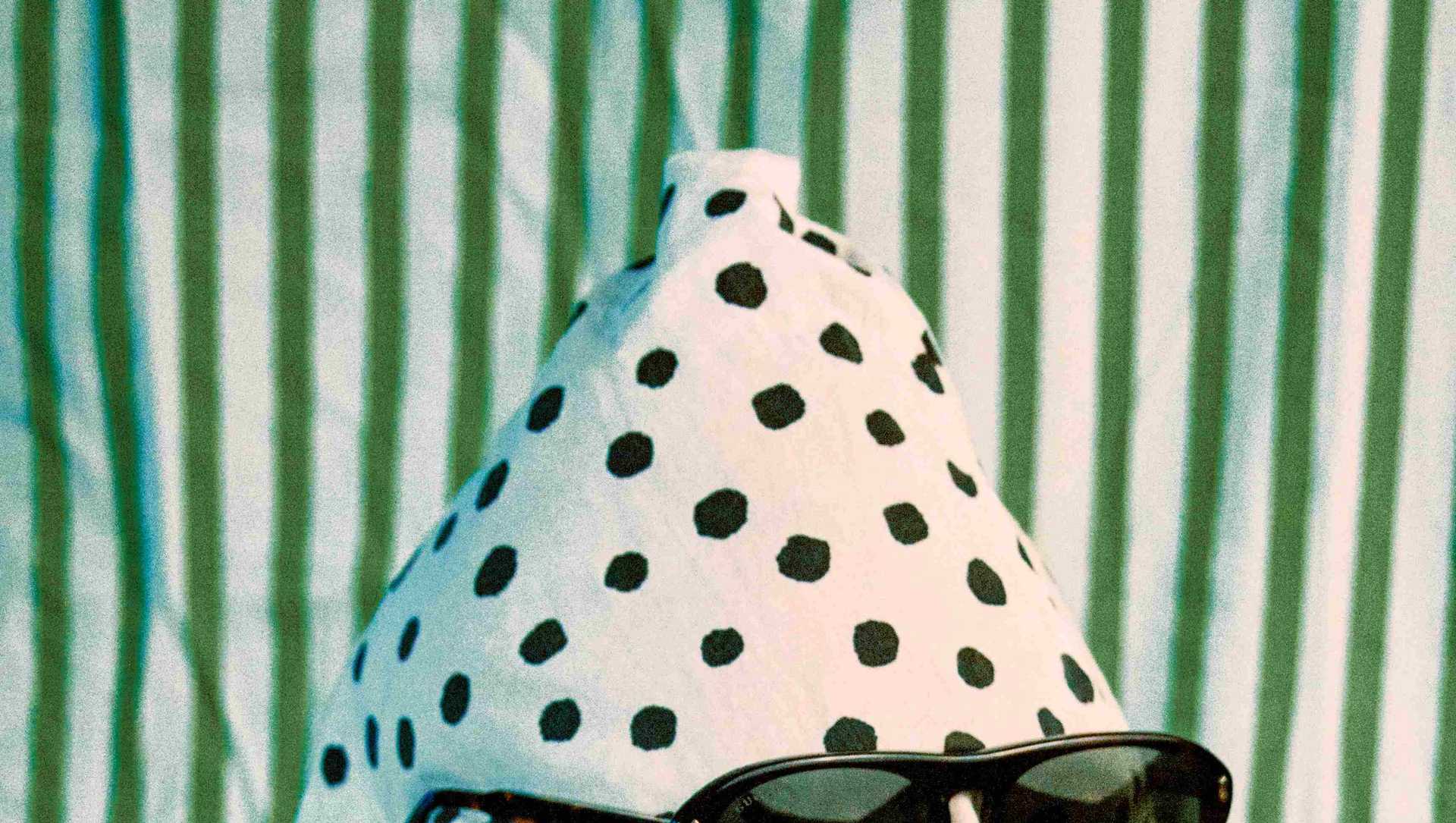 A man with a bag on his head wears sunglasses