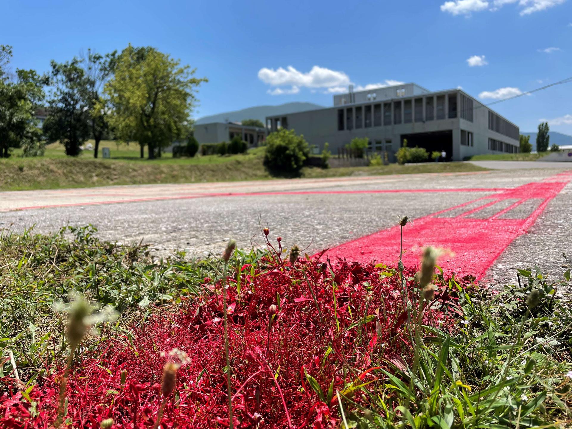 A red line on the grass and the aspahlt of the former military base in Kosovo marks the size of a theater destroyed in Mariupol