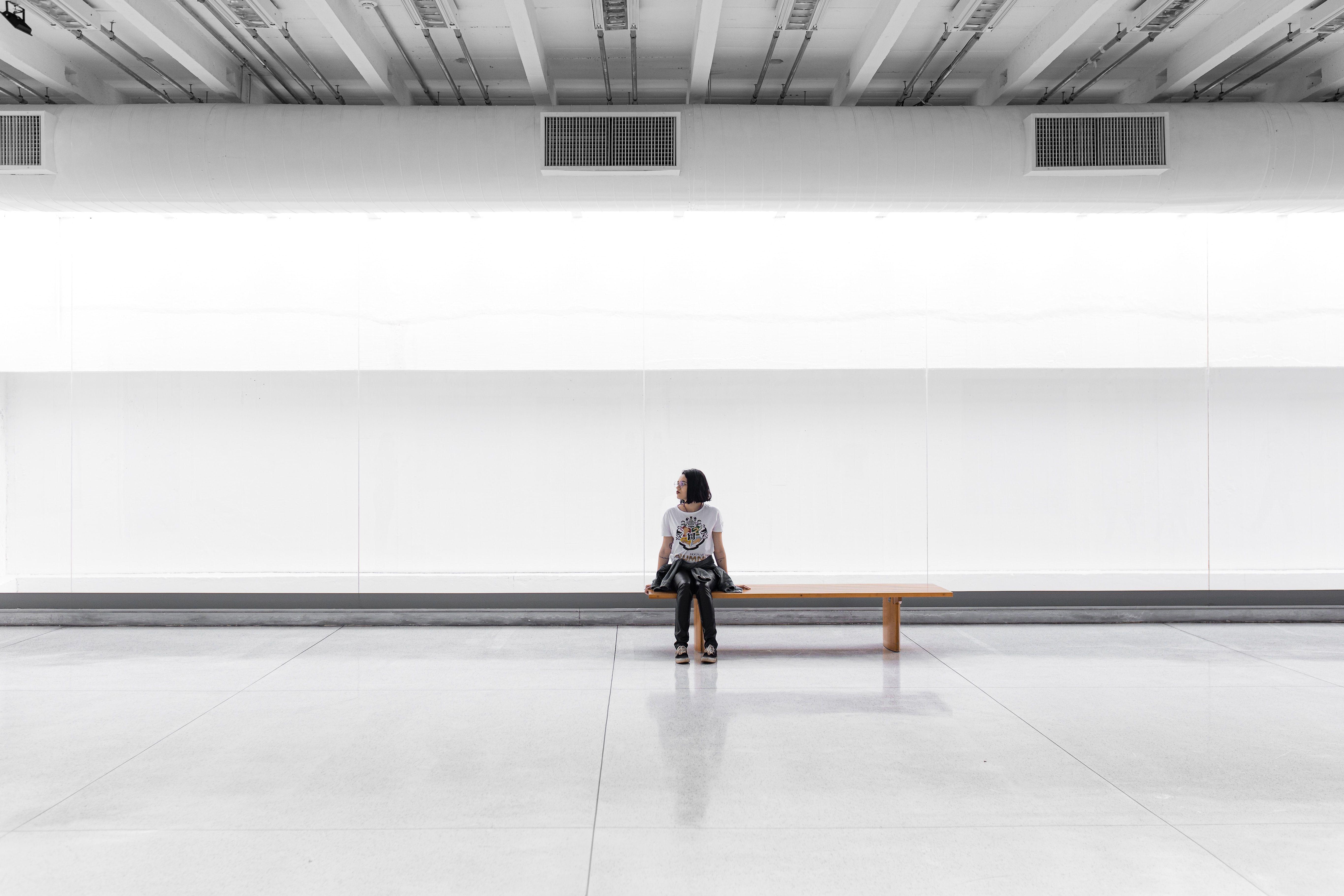 A woman sits on a bench and looks into the room