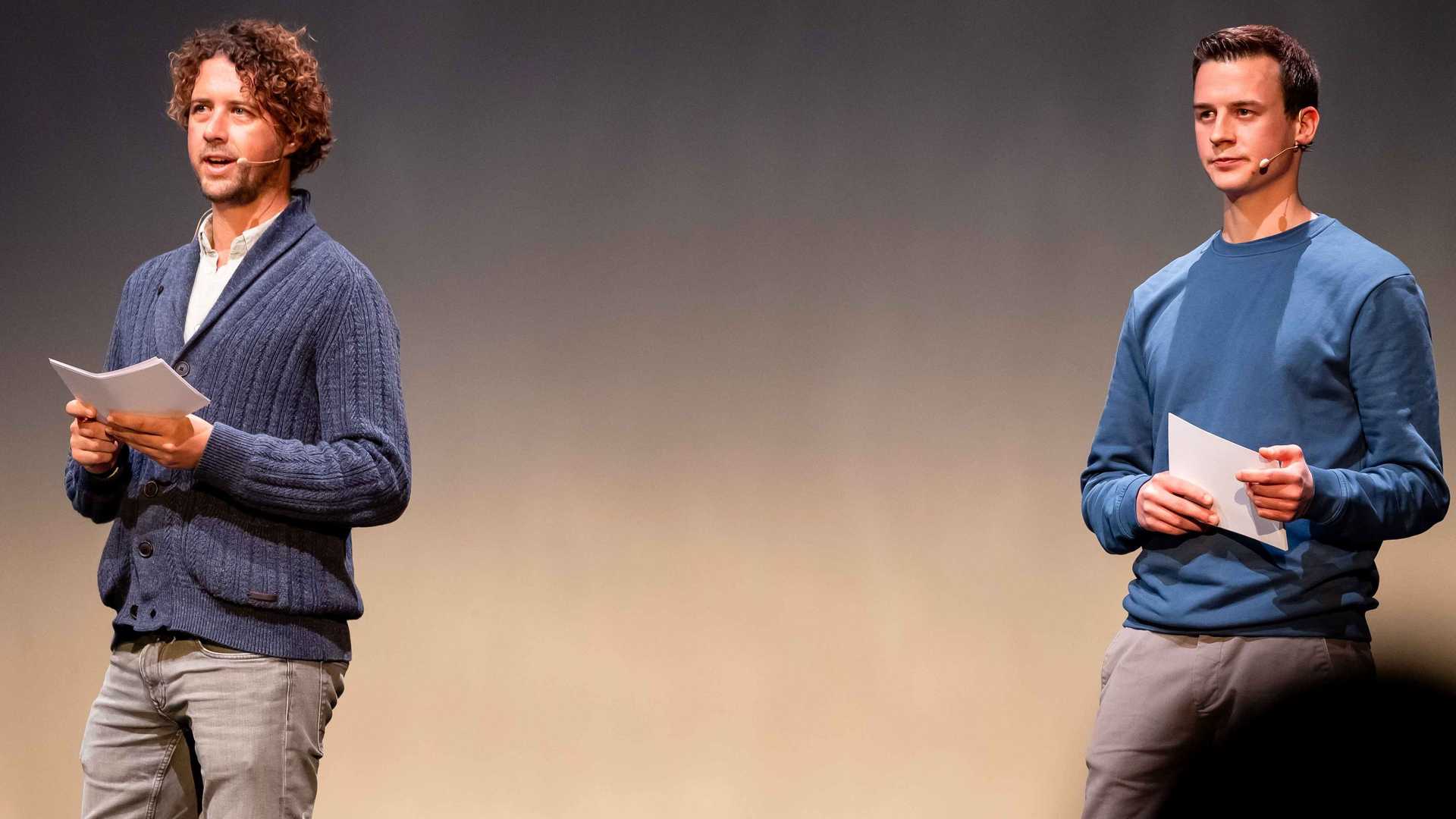 A team of two journalists performs on stage