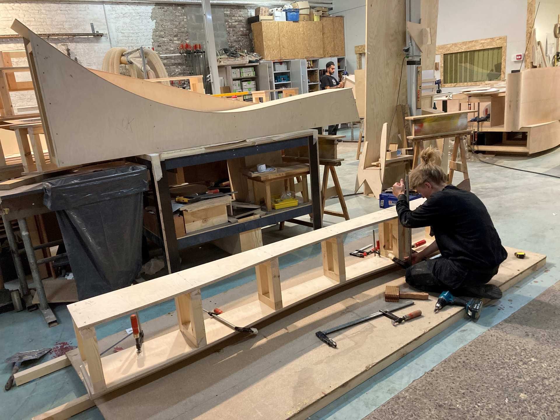 People are working on a wooden structure in of the Recyclarts workshop