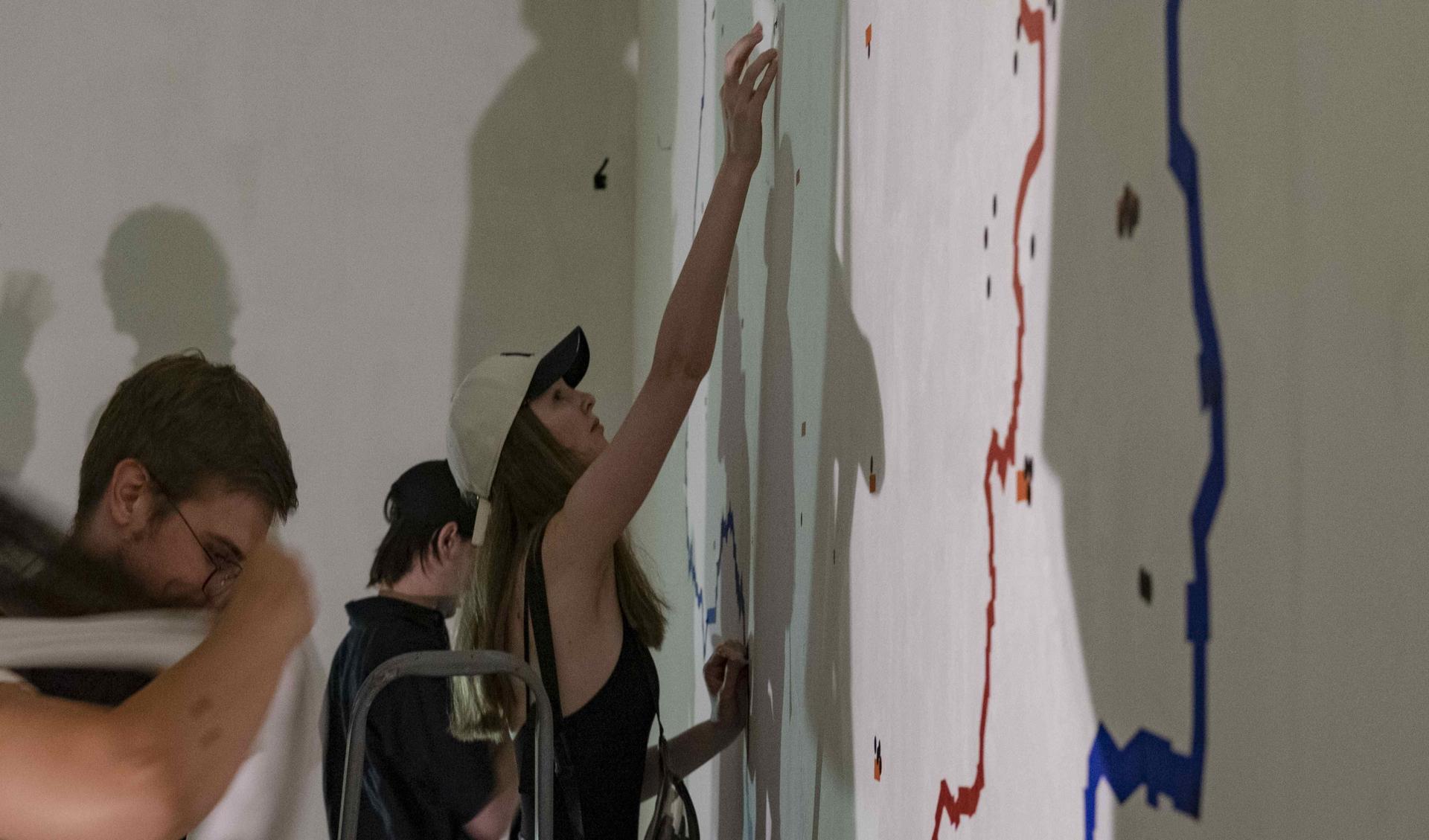 A woman is painting on a wall during an exhibition