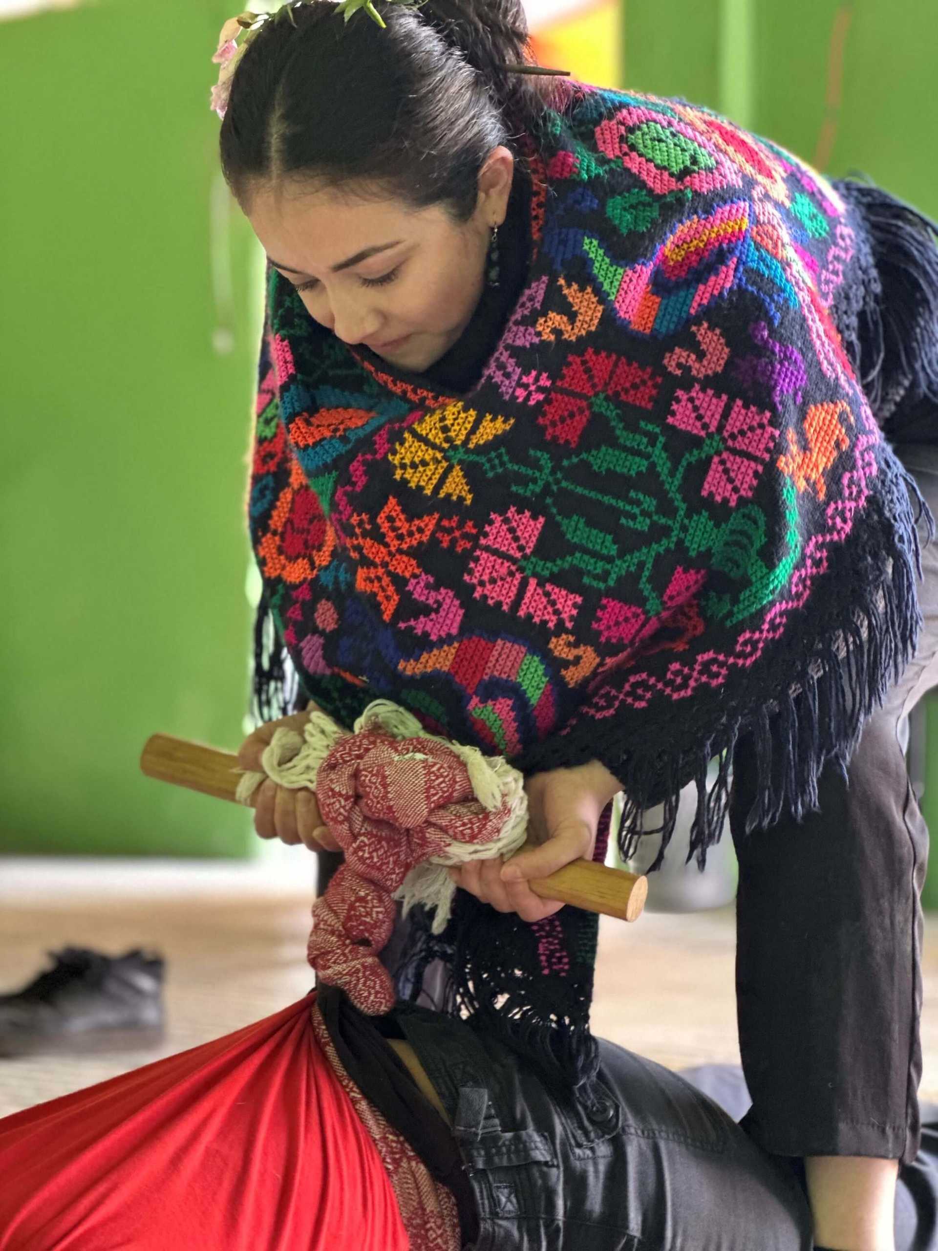 A Midwife i using a rebozo to massage the back of a person