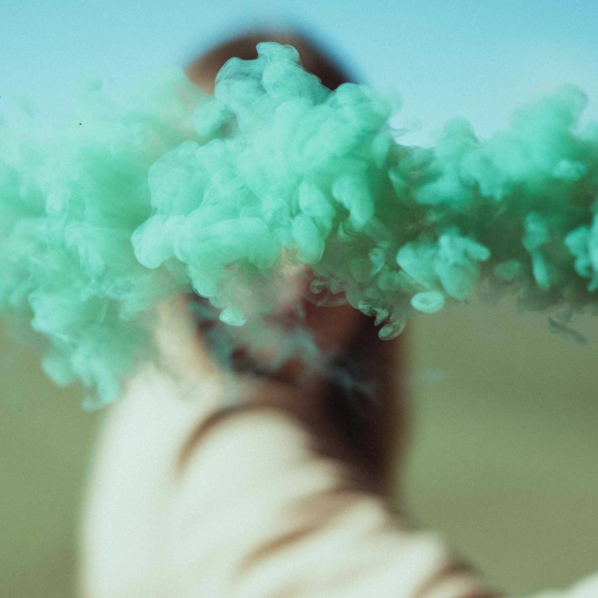A person with green smoke in front of their face