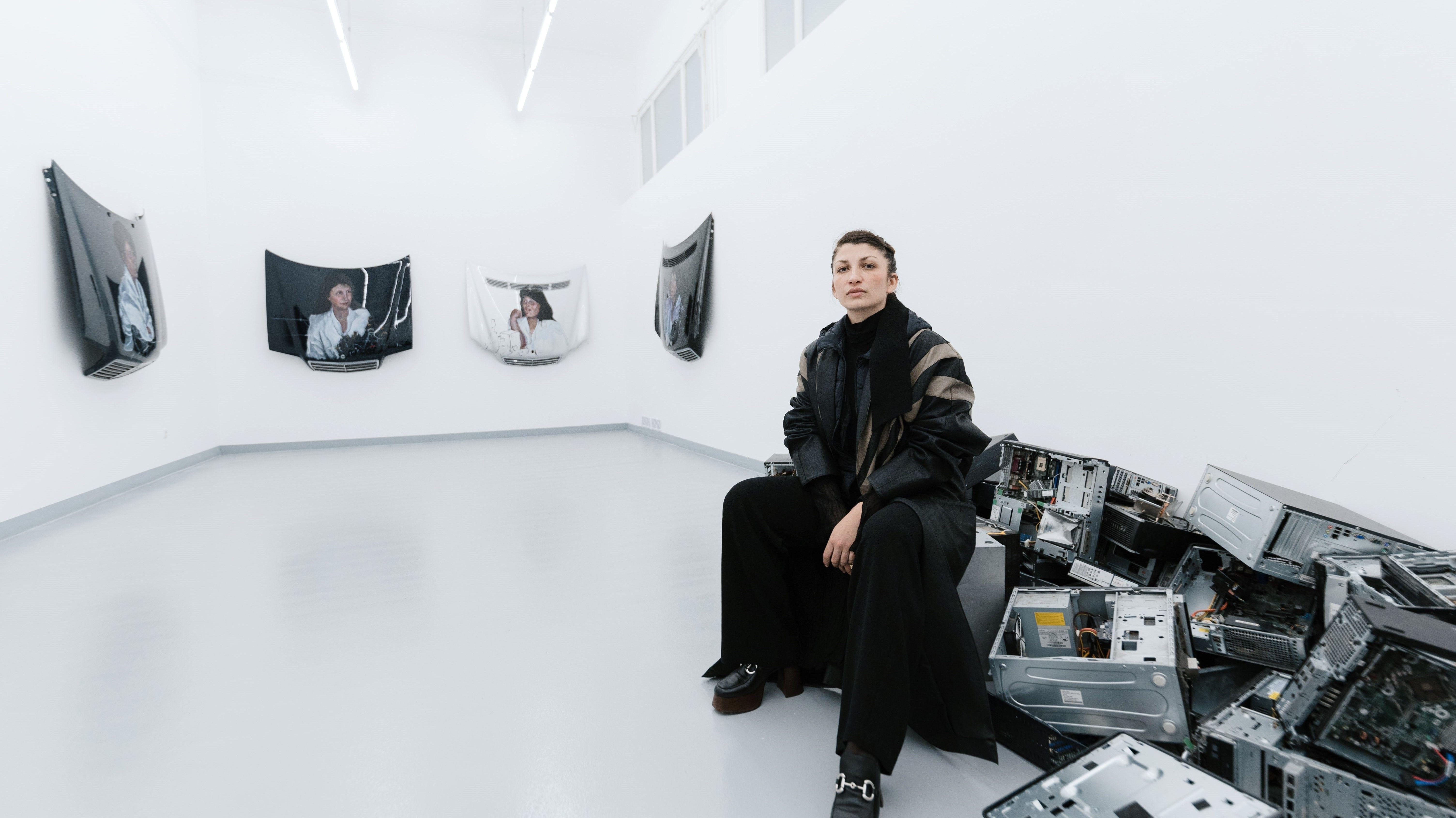 Selma Selman sits in her exhibition full of car pieces